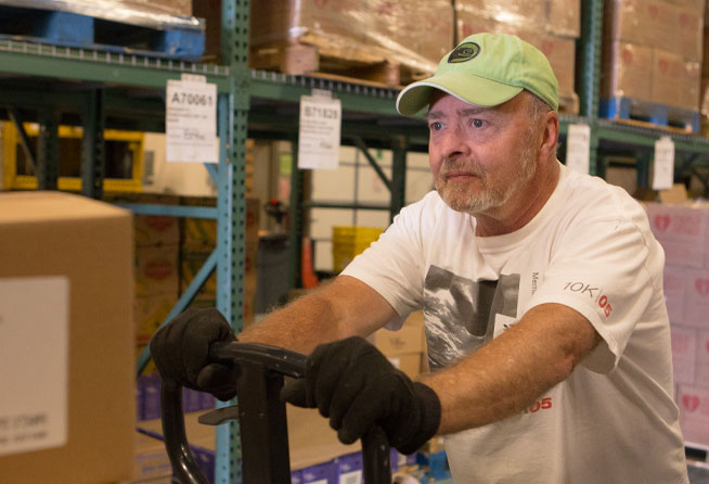 A man pushes a cart of food in the Community Food Share warehouse. 