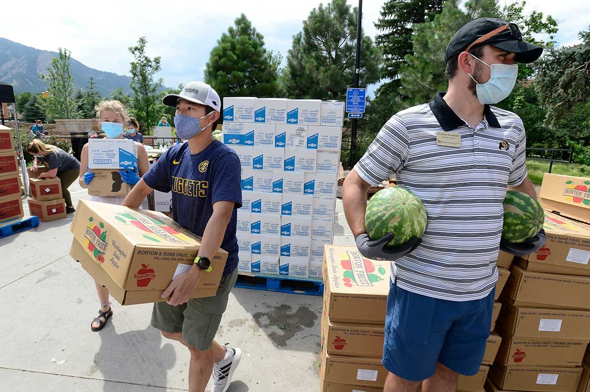 Volunteers carry boxes at a food distribution
