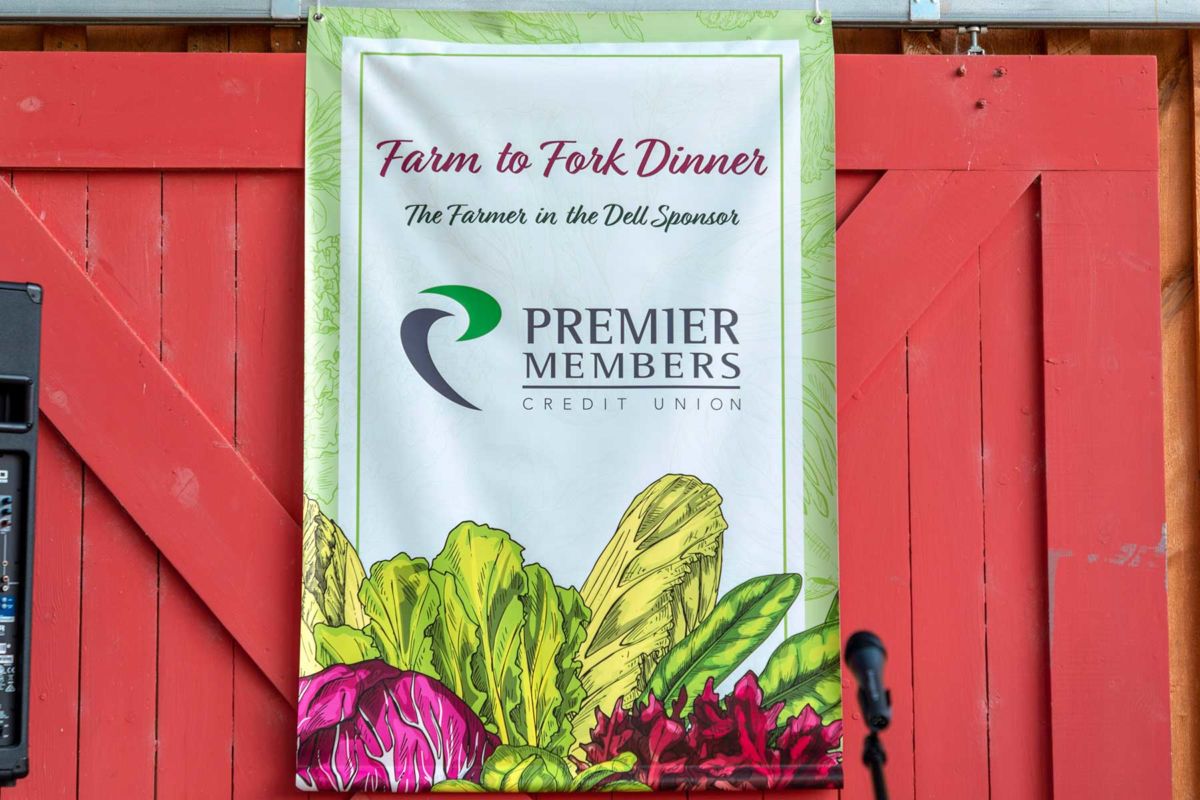 A banner displays the logo of Premier Members Credit Union, who sponsored Community Food Share's Farm to Fork Dinner in 2019