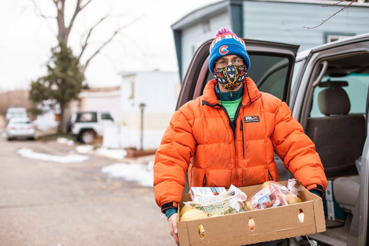 A male program participant unloads fresh produce and pantry staples from his car after a visit to Community Food Share.