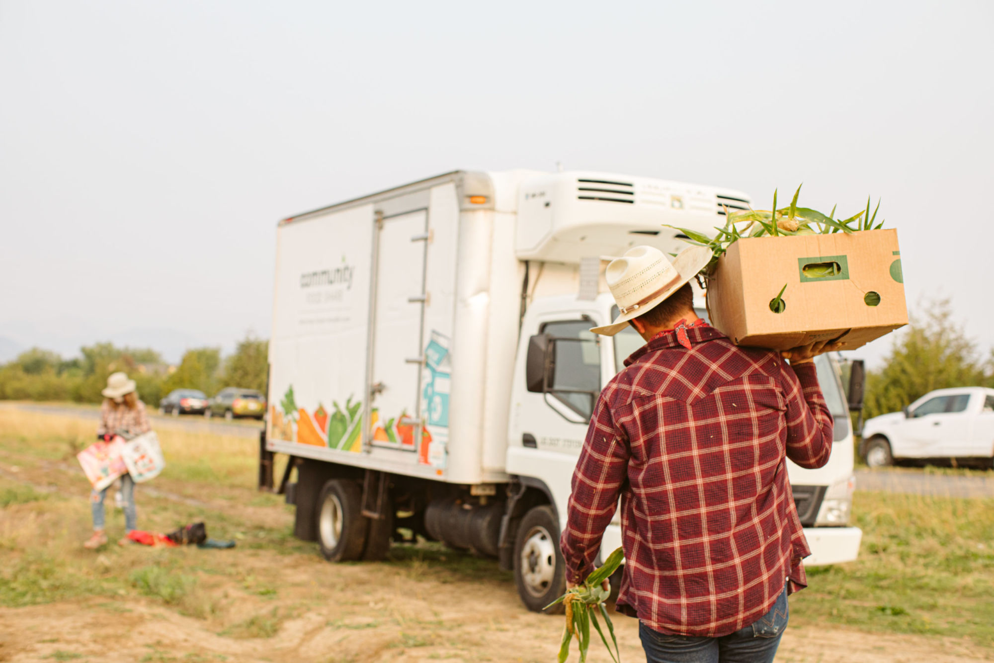 A volunteer carries a box of gleaned produce to a truck.