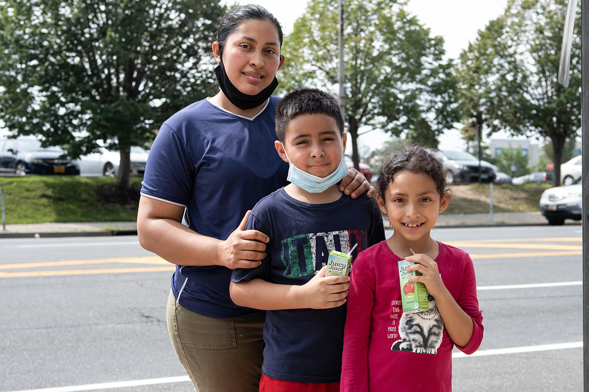 A mother stands behind her two sons at a mobile food pantry