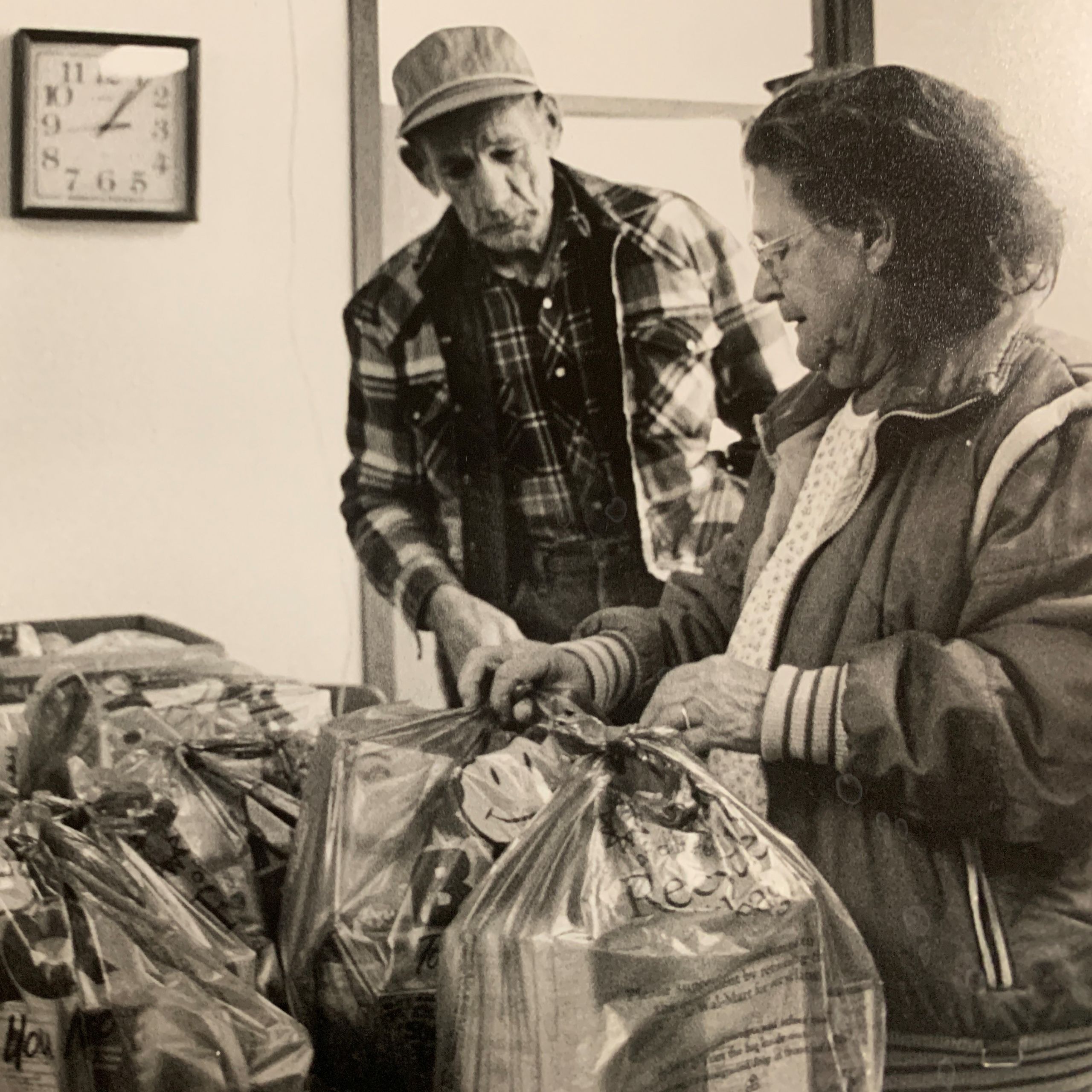 Two seniors collect food from a food pantry in the 1980s