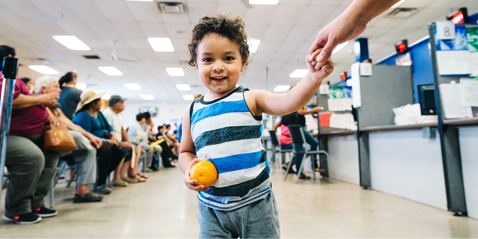 A young boy smiles while holding an orange at a summer meals program